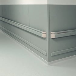 Corner of a hallway with wall cladding, handrails, and wall base.