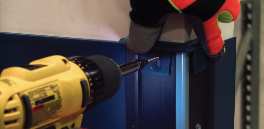 Person attaching a corner guard with a yellow drill.
