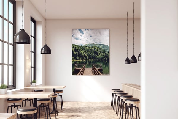 A restaurant wall with a large Inpro digitally printed wall art of a peer on a lake looking out into green mountains and trees to promote biophilic wellness through design.
