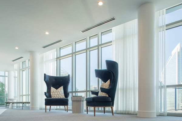 A luxurious lobby or sitting area with a high ceiling and large wall-covered windows with Inpro drapery hanging from them.