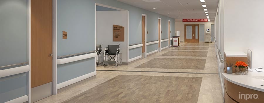 Hospital hallway with blue walls and a wheelchair at the entrance of a connecting hallway