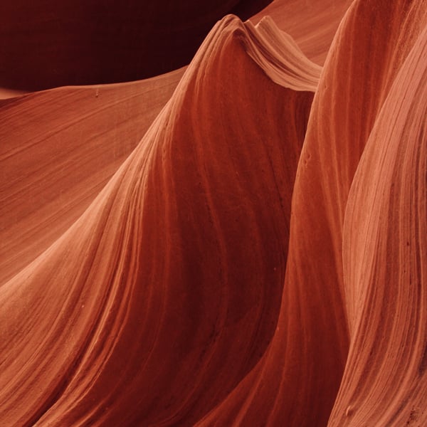 A smooth and wavy red and orange toned rock formation with stressed lines and corrugation. 