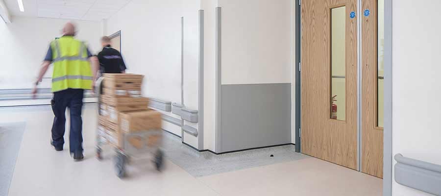 Workers pulling a trolley of boxes down a hallway 