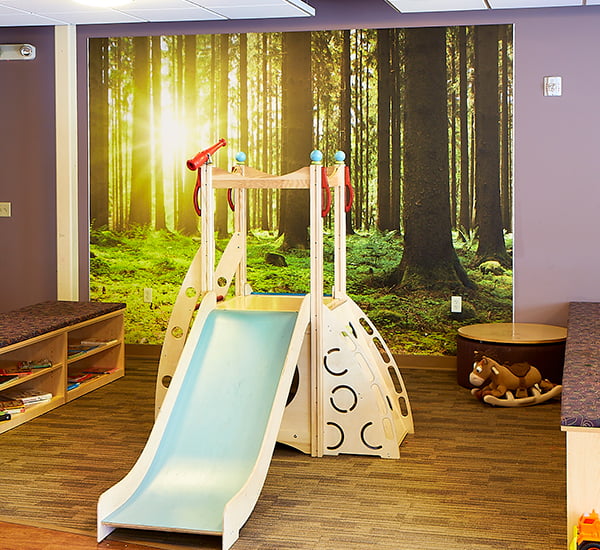 An educational play room displaying biophilic design using Inpro wall art of a forest. 
