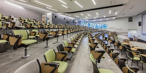 Lecture room in a university hall that incorporates elements of biophilia in education with windows letting in natural light and scenery.
